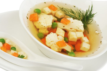 Vegetable soup with cauliflower, potatoes, peas, carrots and dill on a white isolated background