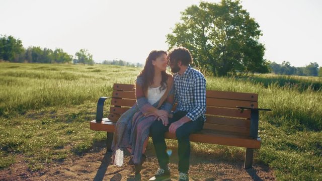 Boyfriend plants a passionate kiss on girlfriend in the park on a beautiful sunny day