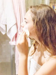Young pretty teen girl in towel is washing her face with foam and brush