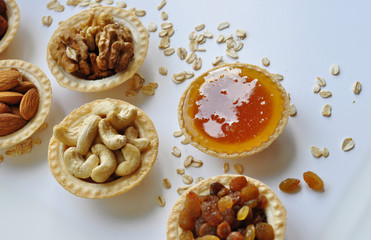 Many different nuts poured into tartlets with honey