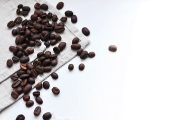 Whole grains of roasted black coffee scattered on a linen towel