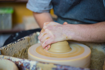 Professional male potter working with clay on potter's wheel