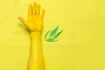 a leaf grows from a hand, yellow backgraund. Top view. Toned.