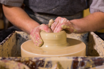 Professional male potter working with clay on potter's wheel