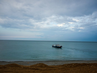 Boat sails to the shore, cloudy weather at sea in summer