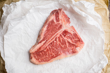 Raw fresh marble T-bone meat on the rustic background. Selective focus. Shallow depth of field.