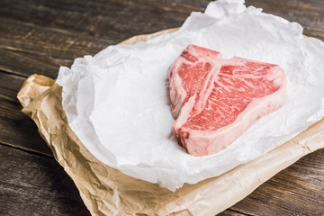 Raw fresh marble T-bone meat on the rustic background. Selective focus. Shallow depth of field.