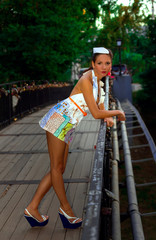 A serious sexy girl stands on the bridge lean for it in a fashionable paper dress looking at the camera