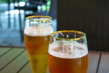 Two transparent glasses of light beer on a wooden table. Soft focus