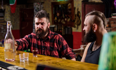 Strong alcohol drinks. Friday relaxation in bar. Friends relaxing in bar or pub. Interesting conversation. Hipster brutal bearded man spend leisure with friend at bar counter. Men relaxing at bar