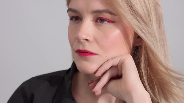 blonde woman with bright red makeup in studio closeup slow motion from 60 fps portrait with hair blowing
