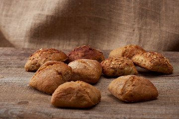 fresh baked buns on wooden table with sackcloth on background