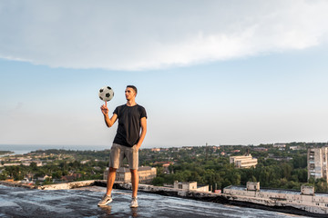 Man playing with ball outdoors on the roof on the background of the city