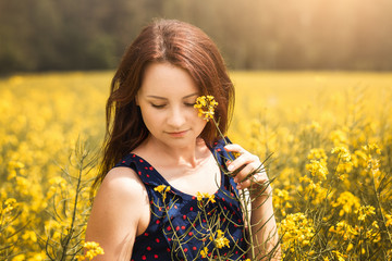 young woman in a field of rapeseed on a sunny day