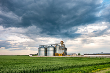 Fototapeta na wymiar agro-processing plant for processing and silos for drying cleaning and storage of agricultural products, flour, cereals and grain with beautiful clouds