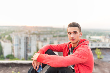 Manly but romantic sport man taking a smartphone or mobile phone photo or picture of sunset on a city rooftop after training