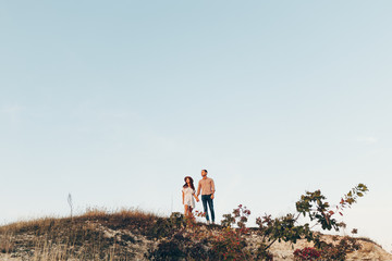 Obraz premium Outdoor shot of young couple in love walking on pathway through grass field. Man and woman walking along tall grass field. 