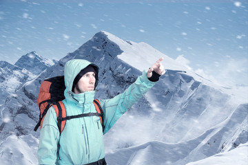 Fototapeta na wymiar Portrait of adventurous young man on winter mountain top view pointing out. Active lifestyle and tourism.
