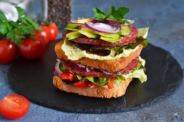 Crispy sandwich with salami, salad and vegetables on the kitchen table. View from above.