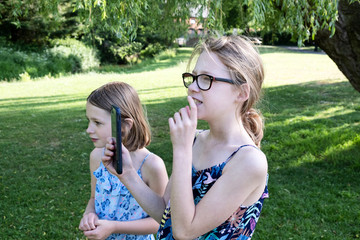 two sisters in the park filming with a mobile phone