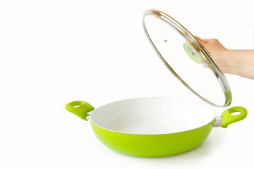 Female hand holding the lid off the pan. Isolated objects on white background