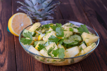 plate of delicious summer salad of pineapple and cucumber on a dark wooden table close-up