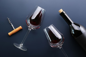 Vintage bottle of red wine with blank matte black label, corkscrew on graphite gradient table background. Expensive bottle of cabernet sauvignon concept. Copy space, top view, flat lay.