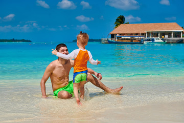 Three year old toddler boy on beach with father. Summer family vacation at Maldives.