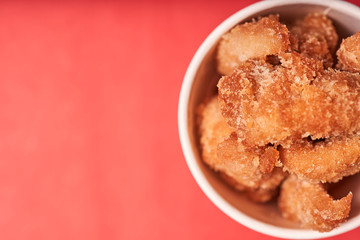 Chicken strips in a paper Cup on a red background.