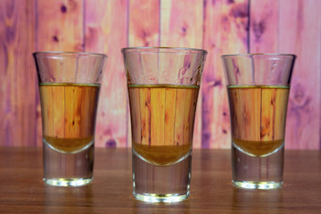 Three glasses of honey liqueur on a wooden table