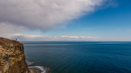 Man standing near the edge of the cliff with beautiful sea view
