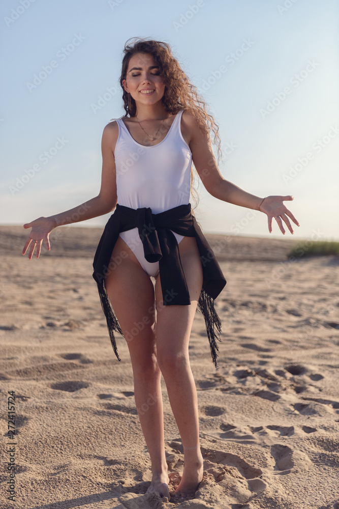 Wall mural beautiful smiling girl on the sand on a hot afternoon