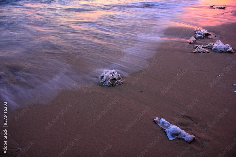 Wall mural plastic garbage, dirty waste on beach in summer day. on the sunset.