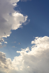 Beautiful blue sky and clouds. Creative vintage background. Very small plane on a background of clouds.
