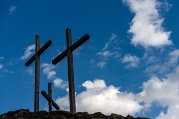 Three Christian crosses above a hill with blue sky and clouds. Religious symbol of good friday