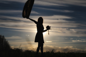 A girl in a hat on a walk in the park. A girl with a basket walks in the spring. A girl is walking along the road at sunset.