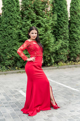 Beautiful brunette in red dress against urban landscape