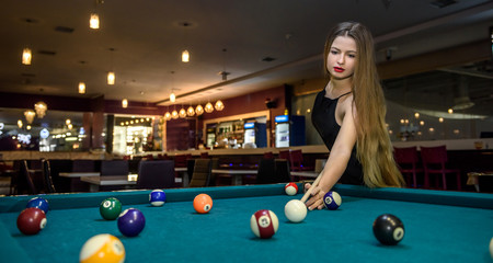 Young and beautiful woman in pub playing billiard - obrazy, fototapety, plakaty