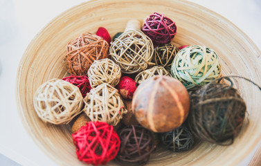 Home details decorations lying on the shelf. Wooden background. Loft style. Cosy rustic mood. Straw and rattan balls in vase.