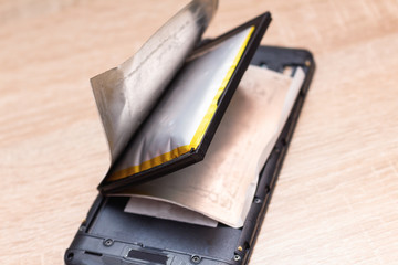 Damaged swollen lithium smartphone battery before explosition ready to catch fire or explode