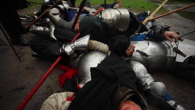 The murdered medieval knights crusaders lie on the ground on the battlefield.