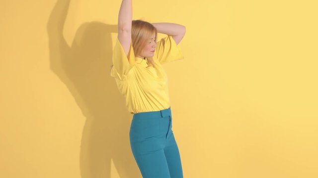 young woman in bright clothes on bright yellow background in studio dancing alone slowmotion 60 fps