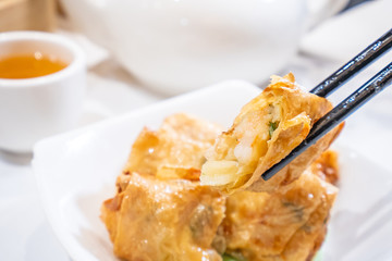 Delicious dim sum, famous cantonese food in asia - Fried bean curd (tofu skin) rolls with shrimp and prawn in hong kong yumcha restaurant, close up