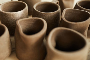 Closeup of handmade ceramic mugs in pottery shop, copy space - obrazy, fototapety, plakaty