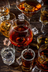 Assortment various hard and strong alcoholic drinks in different glasses: vodka, cognac, tequila, brandy and whiskey, grappa, liqueur, vermouth, tincture, rum, etc. Wooden background copy space