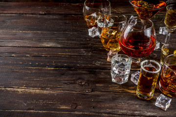 Assortment various hard and strong alcoholic drinks in different glasses: vodka, cognac, tequila, brandy and whiskey, grappa, liqueur, vermouth, tincture, rum, etc. Wooden background copy space