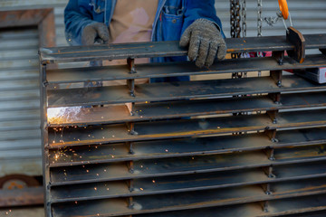 Industry worker welding iron pieces at work.