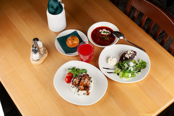 Top view of a three course set menu: traditional russian borscht, beef steak with rice and salad
