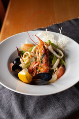 Seafood made dish with king prawns, mussels, squid, greens and citrus as an appetizer in a fancy expensive restaurant