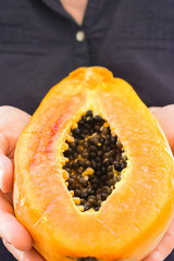 Young Caucasian woman holds in hands ripe juicy cut in half papaya. Healthy lifestyle plant based vegan diet concept. Summer vacation tropical travel theme. Copy space